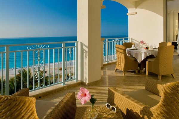 A set table and wicker chairs on the terrace overlooking the blue sea