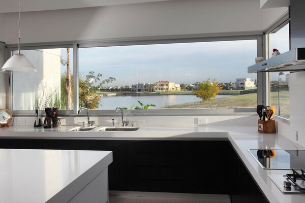 Кухня с рабочей поверхностью у окна с открывающимся видом на озеро и дома