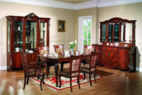 The dining room is in a classic style with brown carved furniture and a door leading to the garden