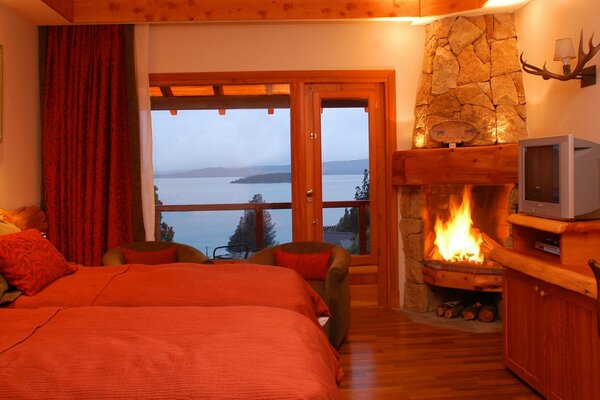 A bedroom with a fireplace, from the window of which a pond is visible