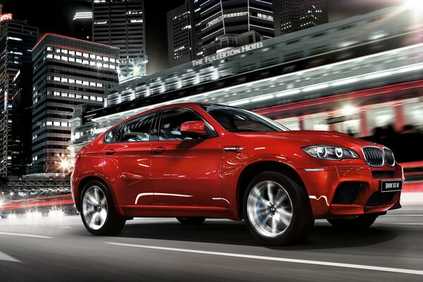 Red BMW x6 on the background of residential buildings