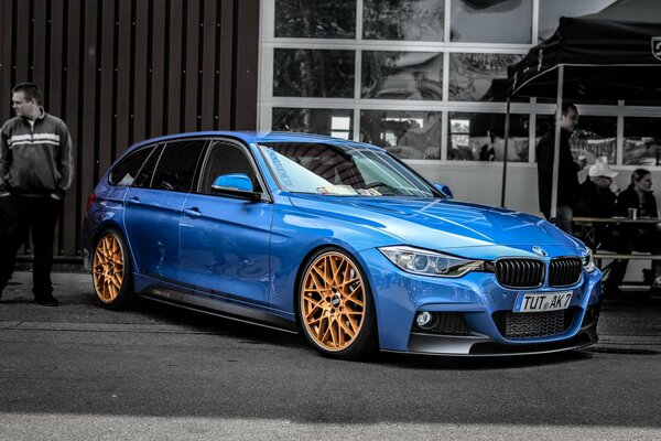 BMW bleu avec roues jaunes sur fond noir et blanc