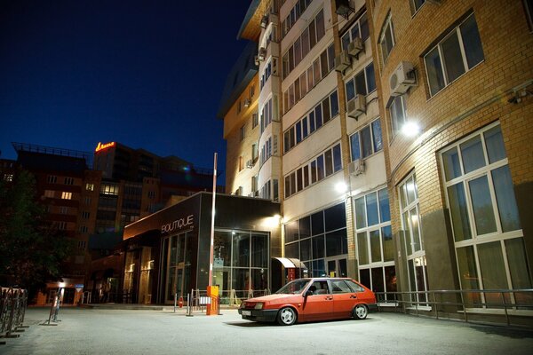 A red Lada parked at a high-rise building