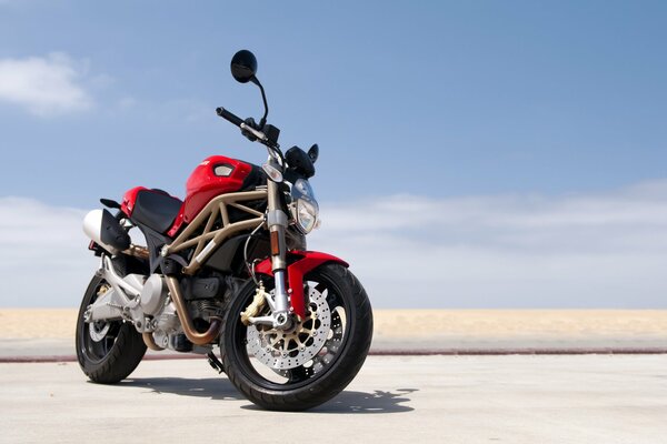 On the beach against the sky - a red sports motorcycle