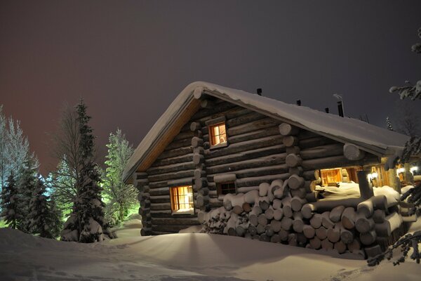 Casa en la noche de invierno con luz en las ventanas