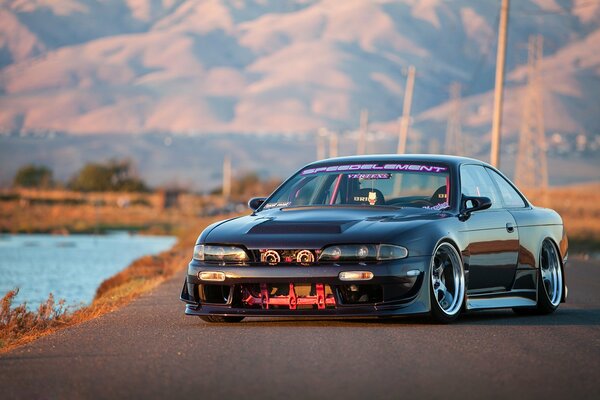 Tuned nissan 240sx on the background of mountains and a pond