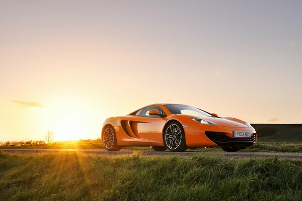 Carta da parati con mclaren MP4-12C arancione brillante sullo sfondo del sole tramontante