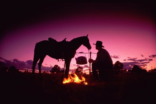 Cow-Boy avec un cheval a fait un feu de joie dans la soirée