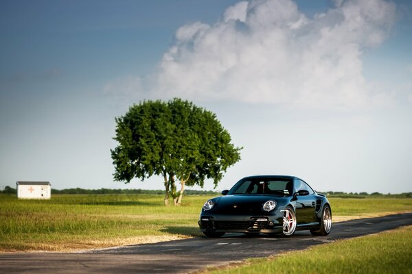 Black Porsche on a background of clear sky and wood