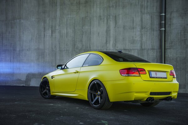 Giallo auto a due porte su sfondo muro di cemento