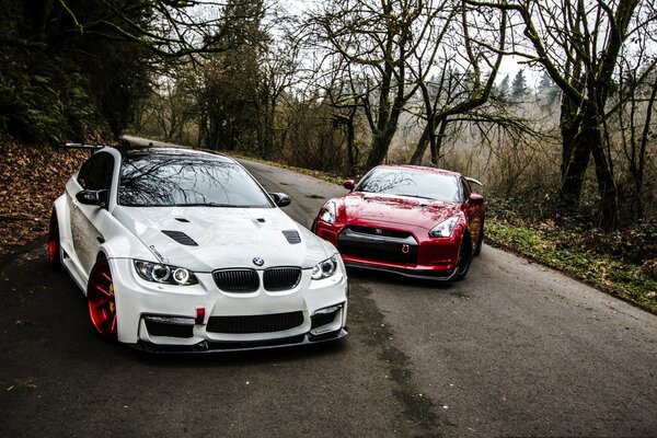 White BMW and red Nissan on the forest autumn road