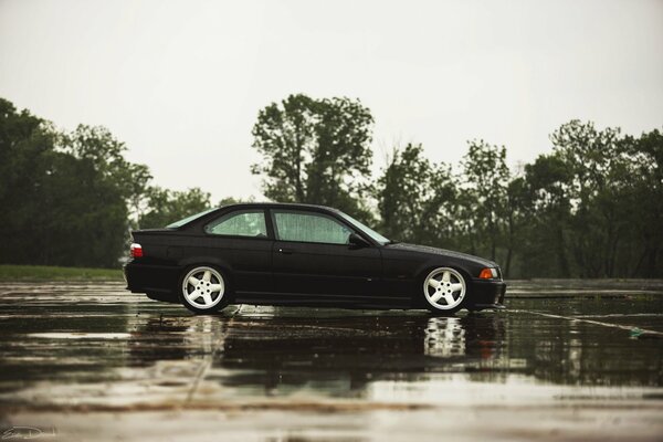 The car is black in the parking lot after the rain