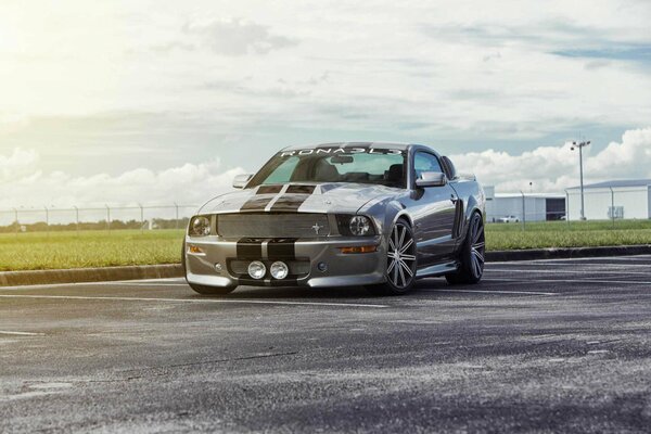 A silver Ford Mustang is driving on the road