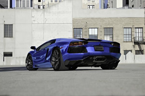 Lamborghini LP700-4 scintillant bleu sur asphalte près d un bâtiment gris avec des fenêtres