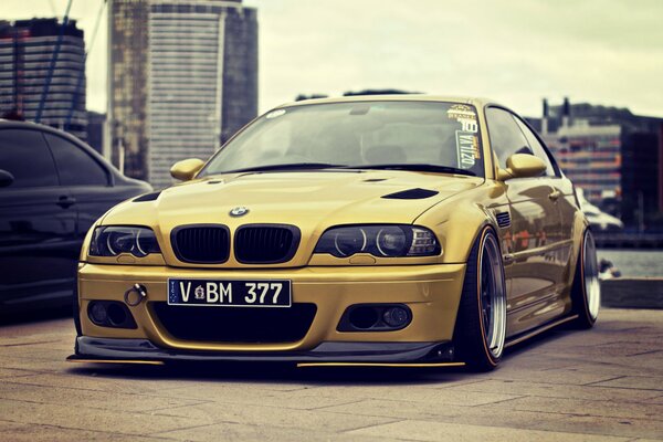 Golden tuned BMW M3 on the background of urban buildings