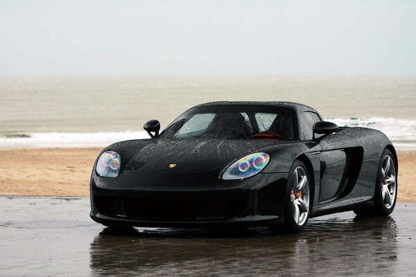 Black Porsche on the beach sand and sea
