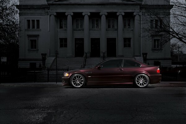 Burgundy bmw on the background of a gloomy building