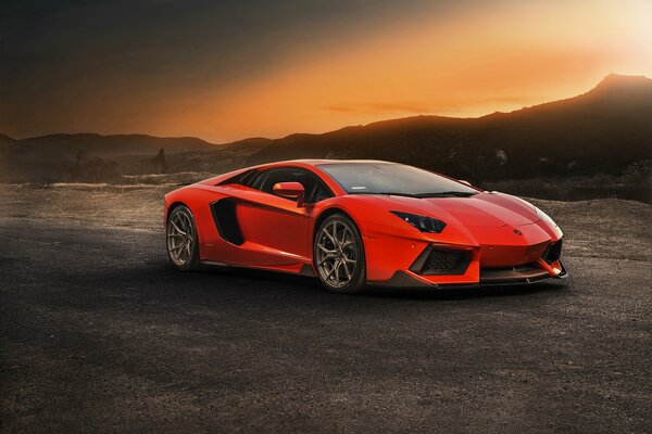 Red car on the background of mountains at sunset