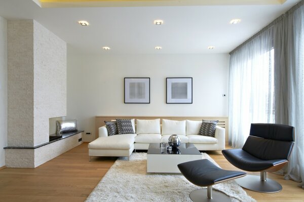Studio-Apartment mit weißem, großem Sofa und schwarzen Stühlen