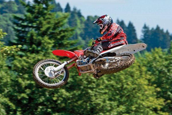 Flying on a motorcycle. Biker on the background of the sky and trees