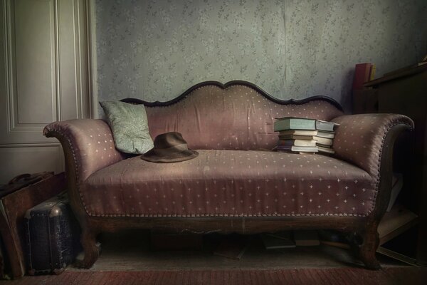 An old sofa with suitcases and a hat