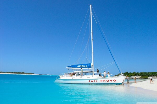 A sailboat with vacationers sets sail from the beach