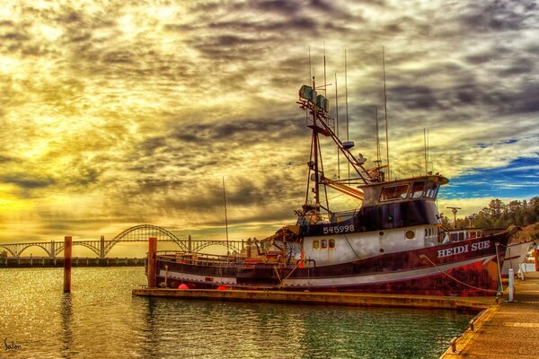 In the painting landscape a ship on a pier in the sunset