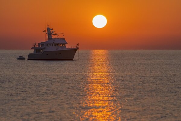 The ship sails at sunset on the sea