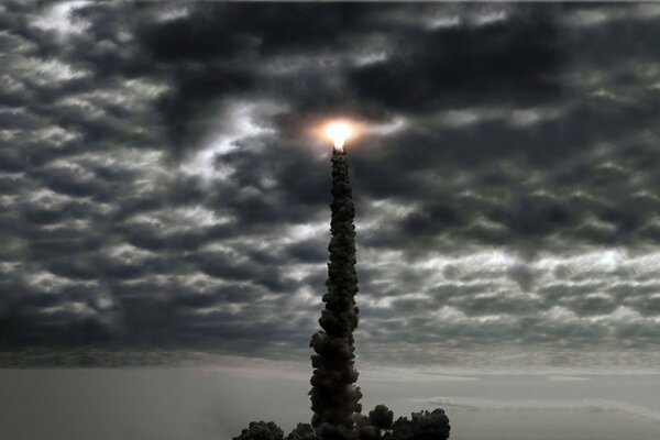 Un brillante resplandor naranja en la parte superior de un pilar de piedra contra las nubes de tormenta