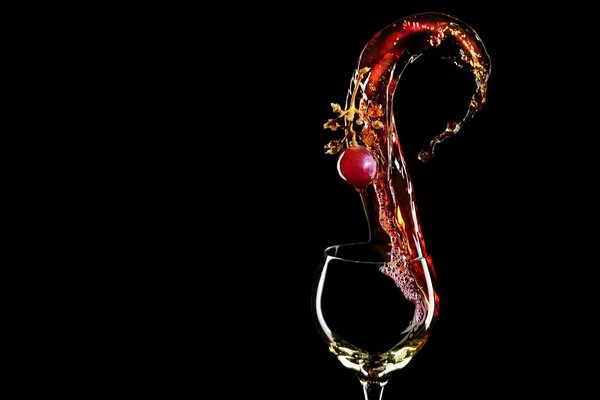 Una ciliegia cade in un bicchiere di vino rosso