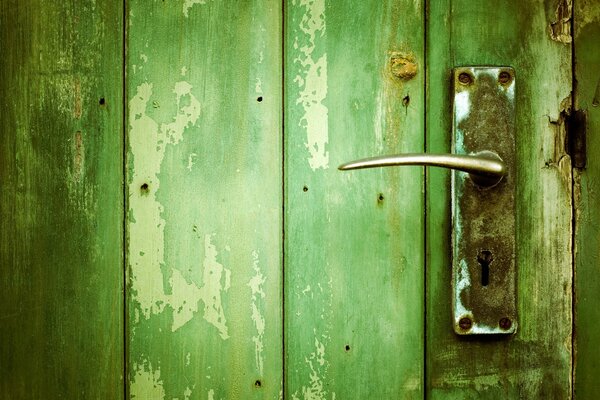 An old door made of green boards with a door lock