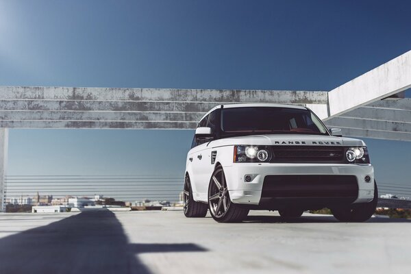 A white SUV stands on concrete