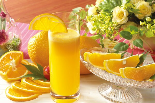 Glas mit Orangensaft und Orangenscheiben in einer Vase