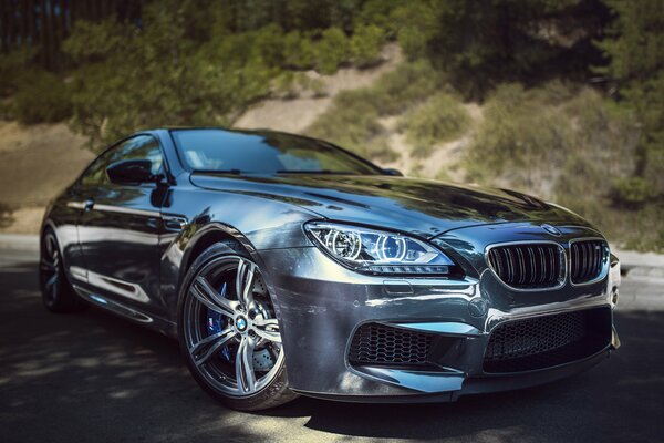 A silver BMW stands against the background of hills