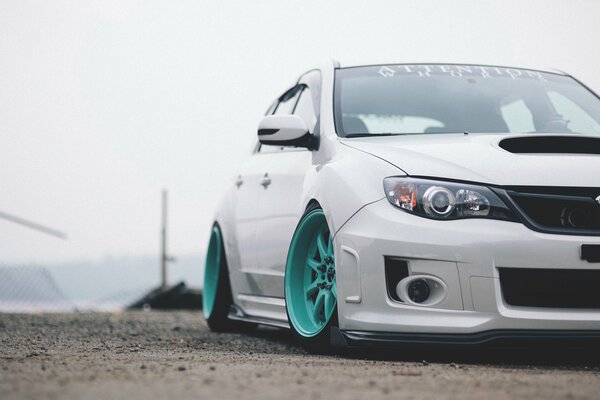 White subaru car with blue wheels