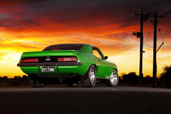 Camaro verde en el fondo de la puesta de sol