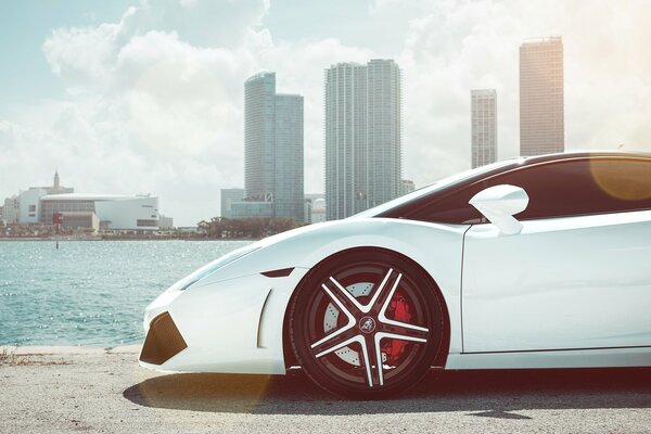 White Lamborghini on the background of the river and skyscrapers