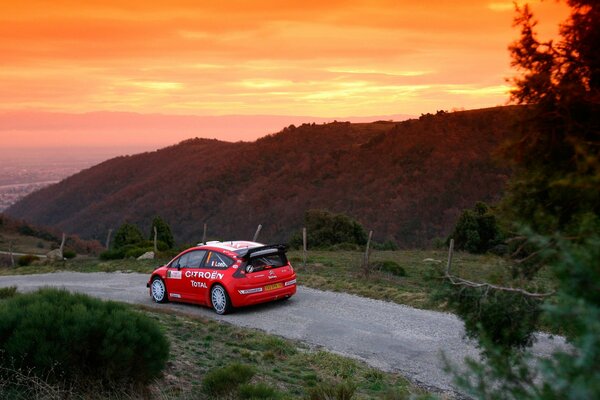 Citroen C4 rojo y puesta de sol en las montañas