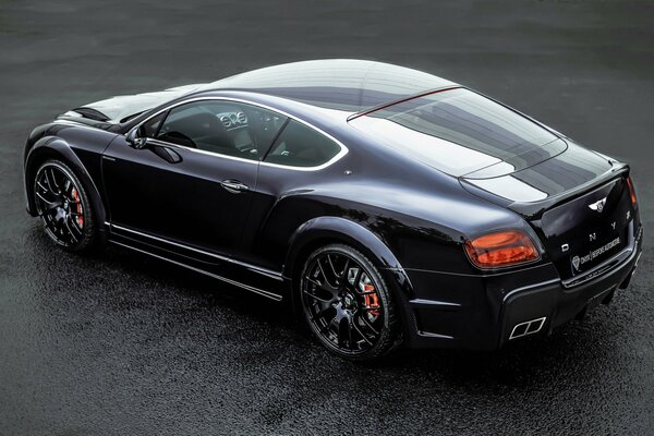 Ein schwarzer Bentley Onyx steht auf nassem Asphalt