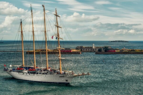 A ship with lowered sails near the lighthouse