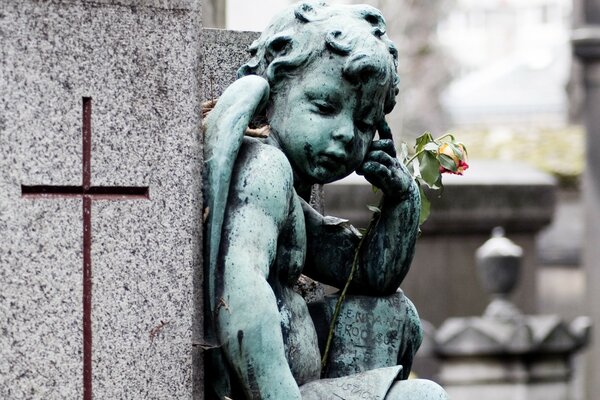 Escultura de ángel con flor sobre fondo gris