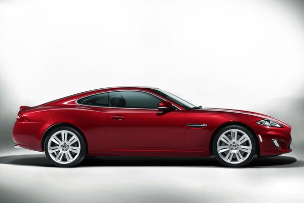 Burgundy Jaguar coupe on a gray background