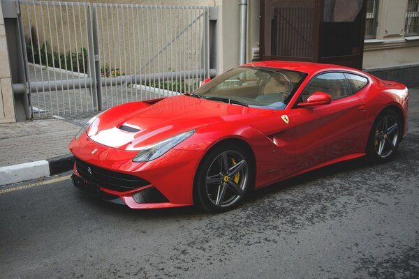 Czerwone Ferrari F12 Berlinetta u bram