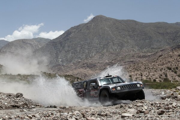 SUV jeep in the mountains rides through a stream