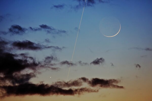 Dunkle Wolken mit einer Spur und einem Mond am Himmel