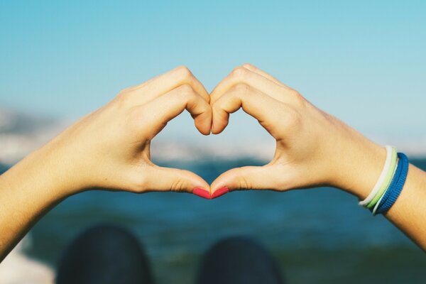 A heart from the hands on the background of the sea