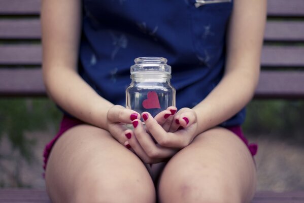 Una chica sostiene un frasco con un corazón de papel