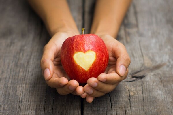 Red apple with a heart in the palms