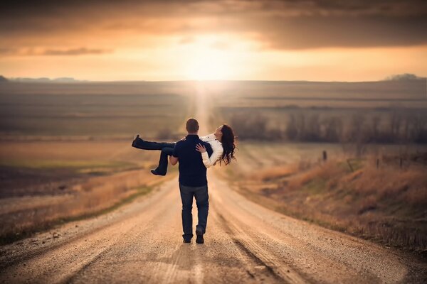 Couple amoureux marchant sur la route en admirant le coucher du soleil