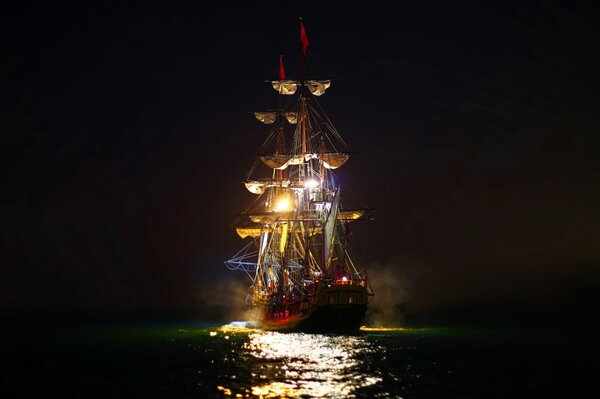 Luces nocturnas de un velero navegando por el mar